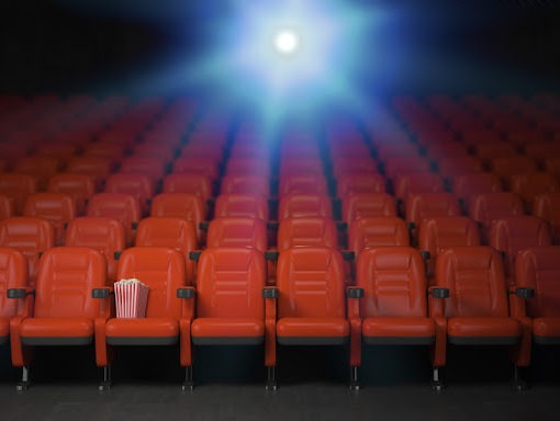 fotele w sali kinowej, nad którymi widać światło projektora