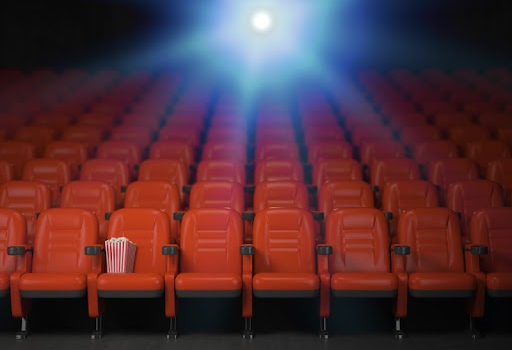 fotele w sali kinowej, nad którymi widać światło projektora