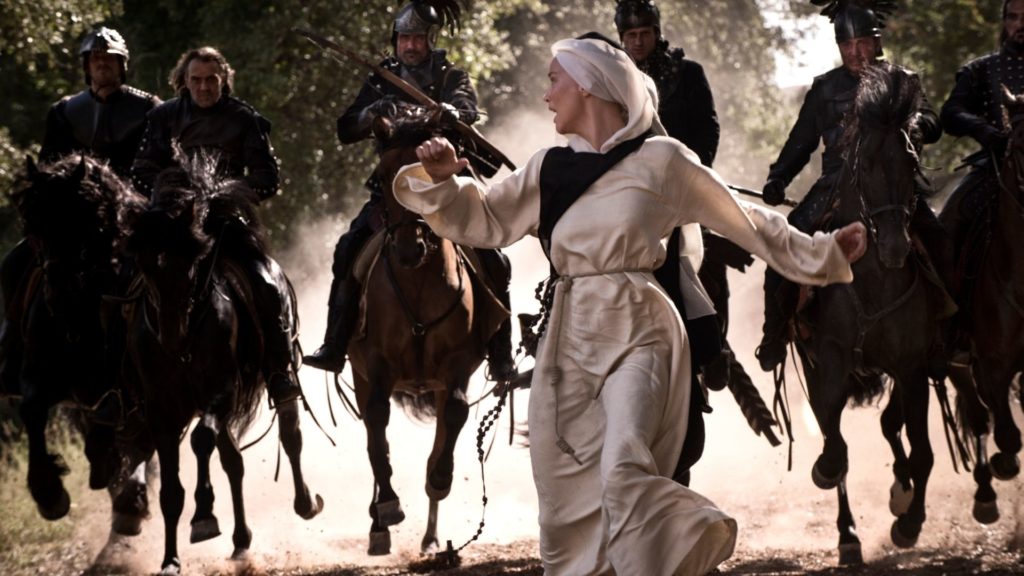 Benedetta ucieka przed rycerzami na koniach. 