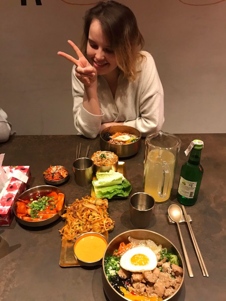 Dziewczyna przy stole z koreańskim jedzeniem.