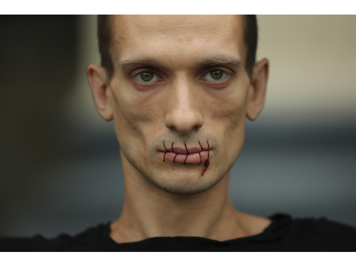 Fotografia na wystawie "Polityka w sztuce" przedstawia mężczyznę z zasznurowanymi ustami. 