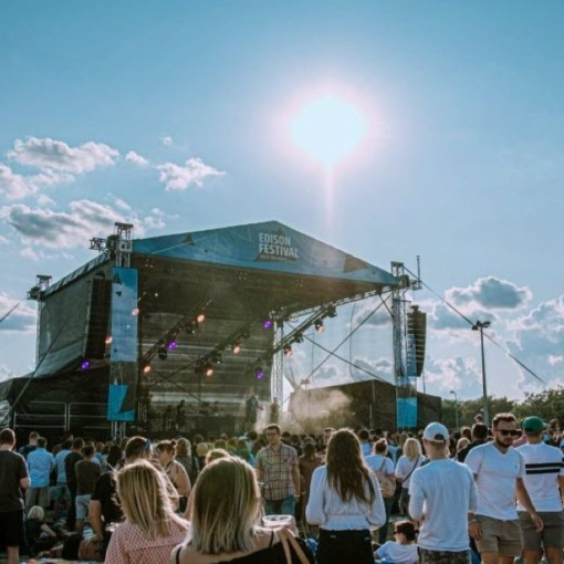 obrazek przedstawiający koncert plenerowy - scena, słońce, tłum