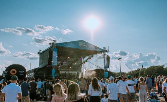 obrazek przedstawiający koncert plenerowy - scena, słońce, tłum