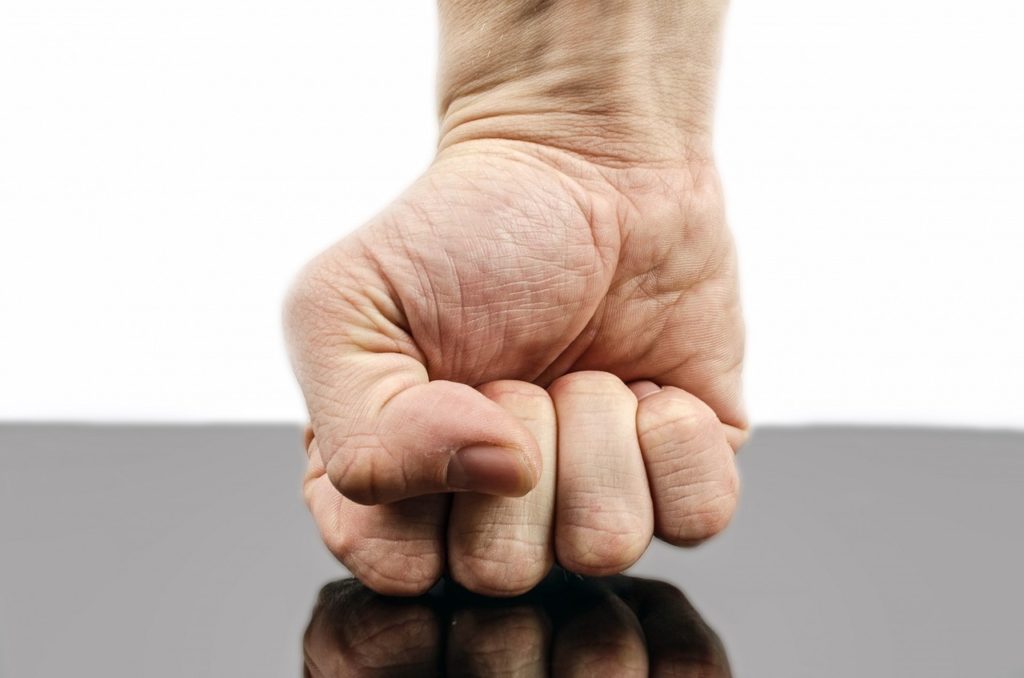 ręka złożona w pięść uderzająca o powierzchnię, być może stół - symbolizuje siłę, agresję, ale też nierzadko męskość