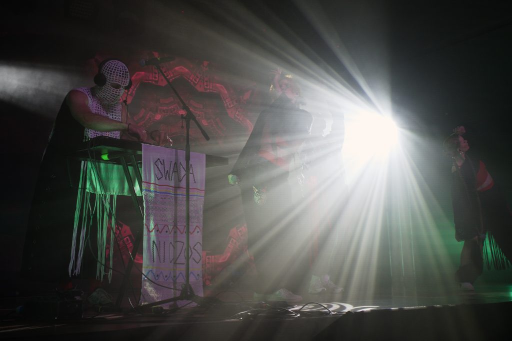 Koncert Sw@da i Niczos, Sw@da operuje za konsolą, gdy występują obok tancerki wraz z Niczos